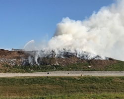 Kaizer Meadow landfill face on fire while Hantsport Fire Department aerial truck fights smoldering blaze.